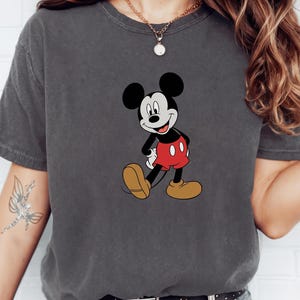 A person wearing a gray t-shirt with a Mickey Mouse graphic printed on it.