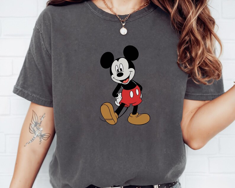 A person wearing a gray t-shirt with a Mickey Mouse graphic printed on it.