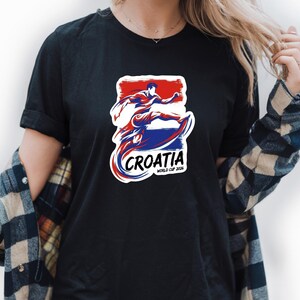 A person wearing a black t-shirt with a graphic design featuring a figure in a red, white, and blue color scheme, along with the text "Croatia" and "WORLD CUP".