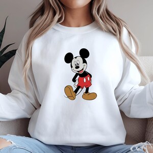A woman wearing a white sweatshirt with a cartoon image of Mickey Mouse printed on it.