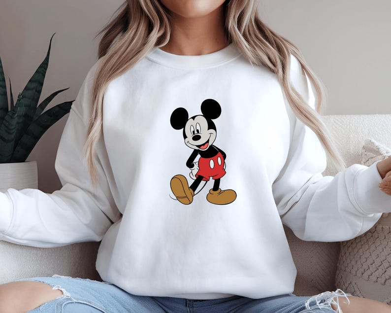 A woman wearing a white sweatshirt with a cartoon image of Mickey Mouse printed on it.
