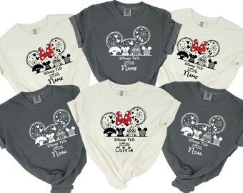 May include: Five gray and cream t-shirts with a black and white Mickey Mouse silhouette design. The shirts feature a red bow, fireworks, and the text "Disney Trip 2025" with a personalized name on each shirt.