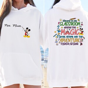 May include: White hoodie with a Mickey Mouse graphic and the text "MRS. MILLER" on the front. The back of the hoodie has a colorful graphic with the text "Welcome to our classroom where the magic never stops and the adventure never ends!"