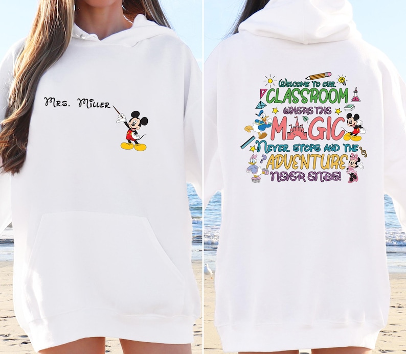 May include: White hoodie with a Mickey Mouse graphic and the text "MRS. MILLER" on the front. The back of the hoodie has a colorful graphic with the text "Welcome to our classroom where the magic never stops and the adventure never ends!"