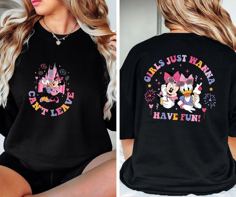 Puede incluir: Sudadera negra con un gr&aacute;fico de Mickey Mouse y Daisy Duck frente a un castillo rosa con fuegos artificiales. El texto "Can't Leave" est&aacute; escrito en un c&iacute;rculo alrededor del gr&aacute;fico. La parte posterior de la sudadera tiene un gr&aacute;fico de Mickey Mouse y Daisy Duck con el texto "Girls Just Wanna Have Fun!" en un c&iacute;rculo alrededor del gr&aacute;fico.