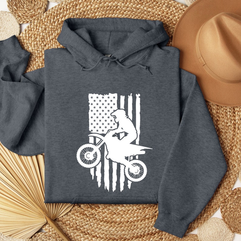 May include: A dark gray hooded sweatshirt with a white graphic of a person riding a dirt bike in front of an American flag.