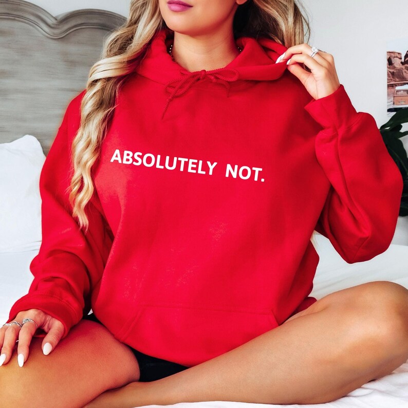 Op de afbeelding: Een rood hoodie met de tekst "ABSOLUTELY NOT." in wit gedrukt op de voorkant.