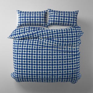 May include: A bedding set featuring a duvet cover and two pillowcases. The set has a repeating pattern of blue and navy blue circles on a cream background. The duvet and pillowcases are made of a soft fabric.