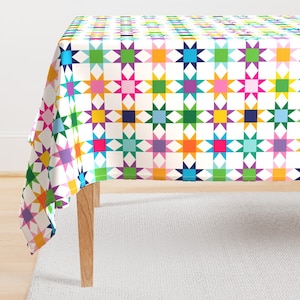 May include: A white tablecloth with a colorful geometric pattern of stars. The tablecloth is made of a soft, durable fabric and is perfect for adding a touch of whimsy to any dining table.