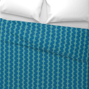 May include: A teal blue and dark blue patterned duvet cover with a white pillow on top.
