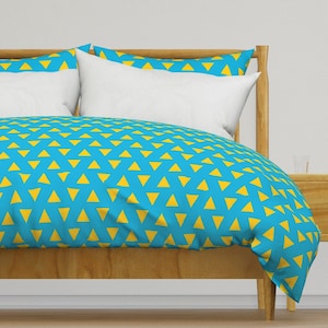 May include: A blue and yellow patterned duvet cover with a wooden bed frame. The duvet cover has a repeating pattern of yellow triangles on a blue background.