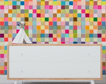 May include: A white dresser with two drawers and wooden trim, featuring a colorful square pattern wall in the background. A small white teepee with black and gold accents sits on top of the dresser.