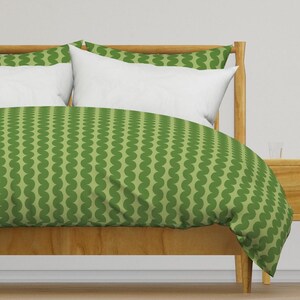 May include: A green and white patterned duvet cover with a wood bed frame. The duvet cover has a repeating pattern of green circles.