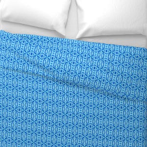 May include: A blue and light blue patterned duvet cover with a white pillow on top.