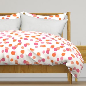 May include: White duvet cover with a pink and orange confetti pattern. The duvet cover is on a bed with a wooden headboard and frame.