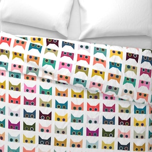 May include: White duvet cover with a repeating pattern of colorful cat faces. Each cat face has two large, round eyes and a simple, stylized shape.