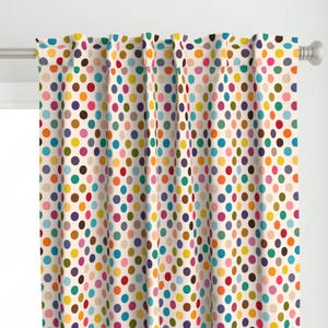 May include: Cream-colored curtain panel with a repeating pattern of colorful polka dots. The dots are in various colors, including red, blue, yellow, green, and brown. The curtain is hanging on a silver rod.