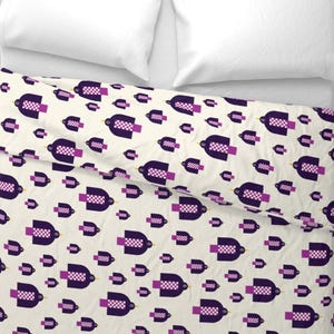 May include: A cream-colored duvet cover with a repeating pattern of stylized purple birds. Each bird has a checkered chest and a purple tail. The birds are arranged in a scattered, repeating pattern across the fabric.