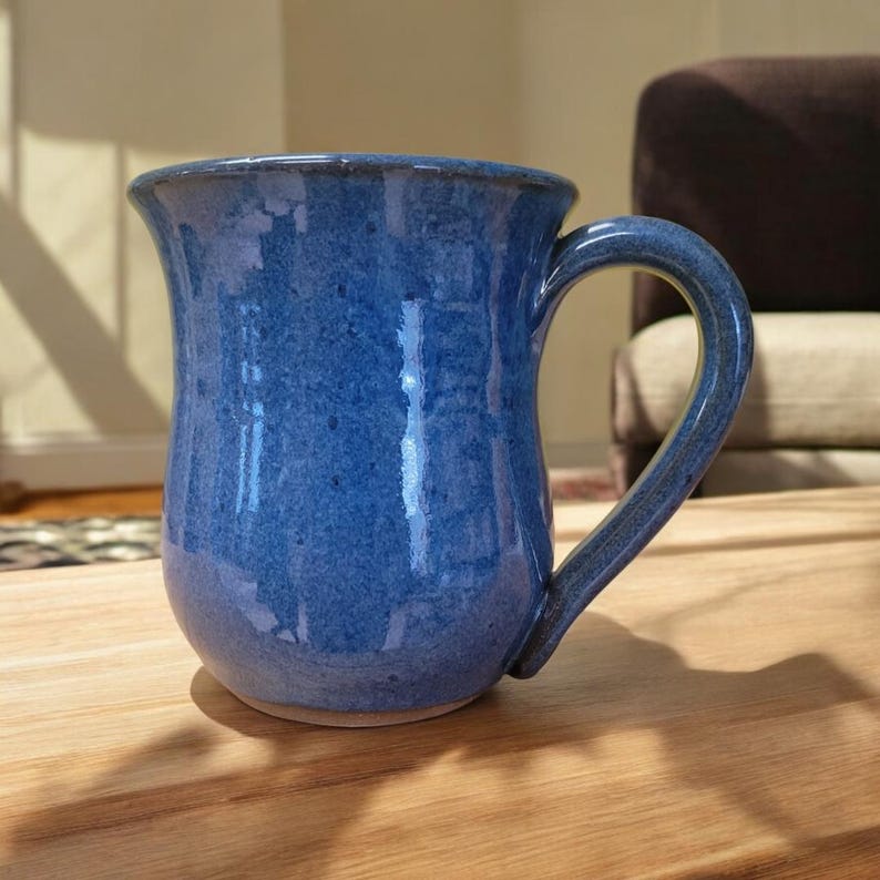 May include: A blue ceramic mug with a rounded body and a handle. The mug has a speckled glaze.
