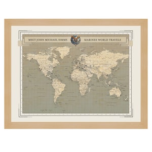 May include: A vintage-style world map with a gray background and black grid lines. The map is framed in a light wood frame. The title "MSGT JOHN MICHAEL SIMMS MARINES WORLD TRAVELS" is displayed at the top of the map. There are small black dots scattered across the map, representing locations.