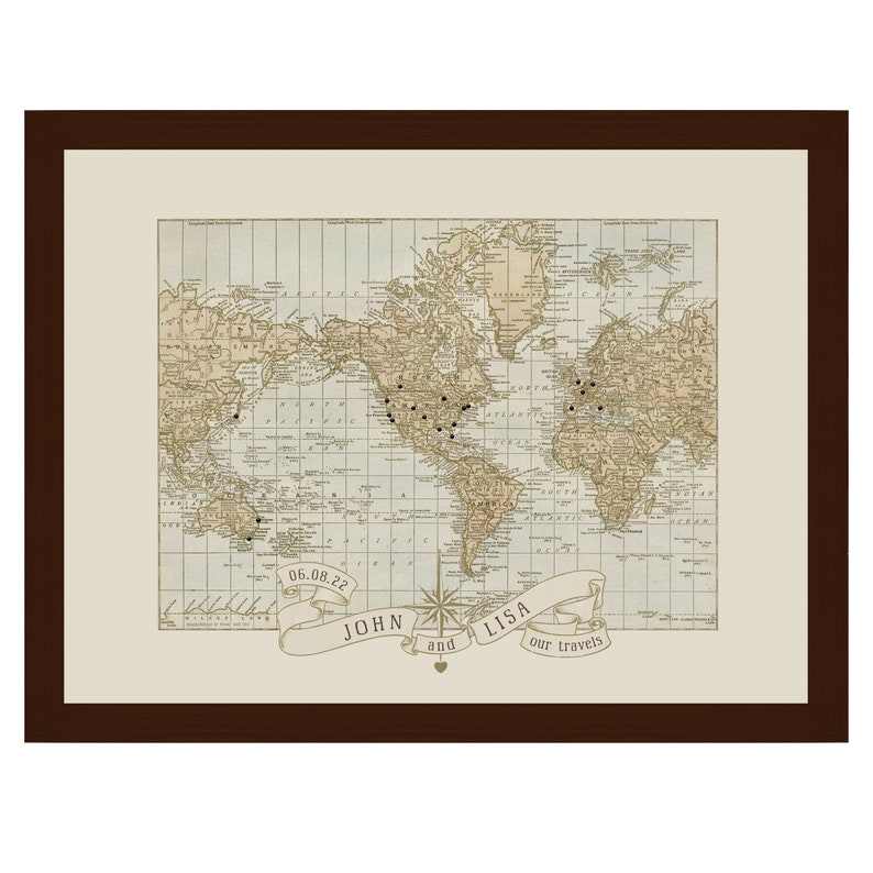 May include: A vintage world map with a brown frame and a banner at the bottom that reads "John and Lisa our travels" with the date "06.08.22". The map is decorated with small black dots, likely representing places visited.