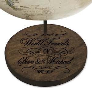 May include: A dark brown wooden globe stand with the text "World Travels of Claire & Michael EST 2018" engraved in black.