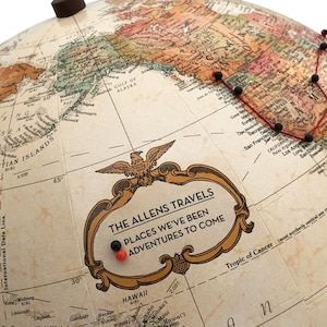May include: A vintage-style globe with a red and black string marking a route across the United States. The globe has a gold frame with the text "The Allens Travels" and "Places We've Been Adventures To Come".