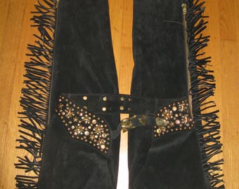 Puede incluir: Chaps de ante negro con adornos de estrellas doradas y pedrería y ribete de flecos.