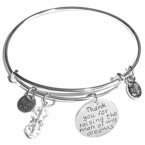 May include: Silver expandable bangle bracelet with charms. The charms include a clear crystal bead, a silver charm with a lotus flower design, and a silver charm with the text "Thank you for the raising of my man of dreams".