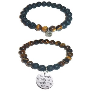 May include: Two bracelets with tiger's eye and lava rock beads. One bracelet has a charm with the text "To teach a child is to touch the future". The other bracelet has a charm with a flower design.