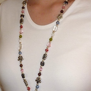 May include: A colorful beaded lanyard with a silver clasp and a silver ring at the end. The beads are various shades of pink, red, green, blue, and brown.