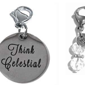 May include: Two silver charm pendants. The first charm is round and has the words "Think Celestial" engraved on it. The second charm has a small silver lotus flower charm and a crystal bead.