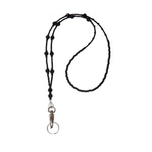 May include: A black beaded lanyard featuring a series of small, uniform black seed beads interspersed with larger, round black accent beads. The lanyard terminates in a silver-toned metal lobster claw clasp and a circular split key ring.