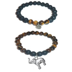 May include: Two stretch bracelets featuring round beads. The top bracelet has black porous lava beads and brown tiger eye beads with a silver-toned lotus flower charm. The bottom bracelet has brown tiger eye beads and black lava beads with a silver-toned elephant charm.
