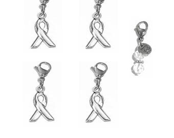 May include: Four silver-toned awareness ribbon charms with lobster claw clasps, and one additional charm featuring a small round metal tag with a lotus flower engraving, a clear faceted bead, and a lobster claw clasp, all arranged on a white background.