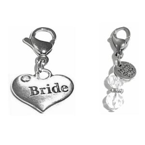 May include: Two silver charm pendants. One is a heart-shaped charm with the word "Bride" engraved on it. The other is a round charm with a floral design and a crystal bead.