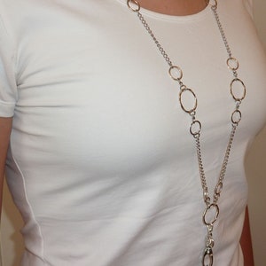 May include: A silver chain necklace with multiple circular links. The chain has a silver clasp at the bottom.