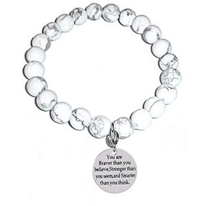 May include: A stretch bracelet composed of round white beads with grey veining. A circular silver-toned metal charm hangs from the bracelet, engraved with the text: You are Braver than you believe, Stronger than you seem, and Smarter than you think.