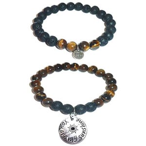 May include: Two beaded bracelets. The top bracelet features black porous lava beads, brown tiger eye beads, and a small silver lotus charm. The bottom bracelet consists of brown tiger eye beads, black lava beads, and a round silver charm with the text "you are my sunshine" and a sun icon.