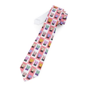 May include: A patterned necktie featuring a repeating design of colorful cartoon cat faces on a pink and white checkered background. The cats are in various colors, including yellow, pink, green, and purple. The tie has a white backing.