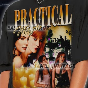 Puede incluir: Camiseta negra con la frase "PRACTICAL MAGIC" en letras doradas. La camiseta presenta un gráfico del elenco de la película y una casa embrujada. El texto "SANDAE VINTAGE" también es visible.