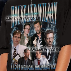 Puede incluir: Camiseta negra con un diseño gráfico con el texto "HOUSE AND WILSON" e imágenes de actores. También se muestra la frase "I LOVE MEDICAL MALPRACTICE". La camiseta tiene una estética vintage.