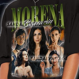 May include: Black t-shirt with a vintage-style graphic of Morena Baccarin. The design includes her name in green and multiple images of the actress. The text "SANDAE VINTAGE" is also visible on the shirt.