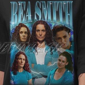 Peut inclure: T-shirt noir avec un imprimé graphique d'un collage d'images d'une femme aux cheveux roux. Le texte "BEA SMITH" est imprimé en lettres blanches au-dessus du collage.