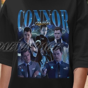 May include: Black t-shirt featuring a blue and white graphic of the characters from the video game "Detroit: Become Human". The graphic includes the text "Connor RK800".