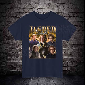 Op de afbeelding: Een marineblauw t-shirt met een grafische print van Jasper Hale uit de Twilight-saga. De grafiek is in goud en zwart met de tekst "Jasper Hale" in goud.