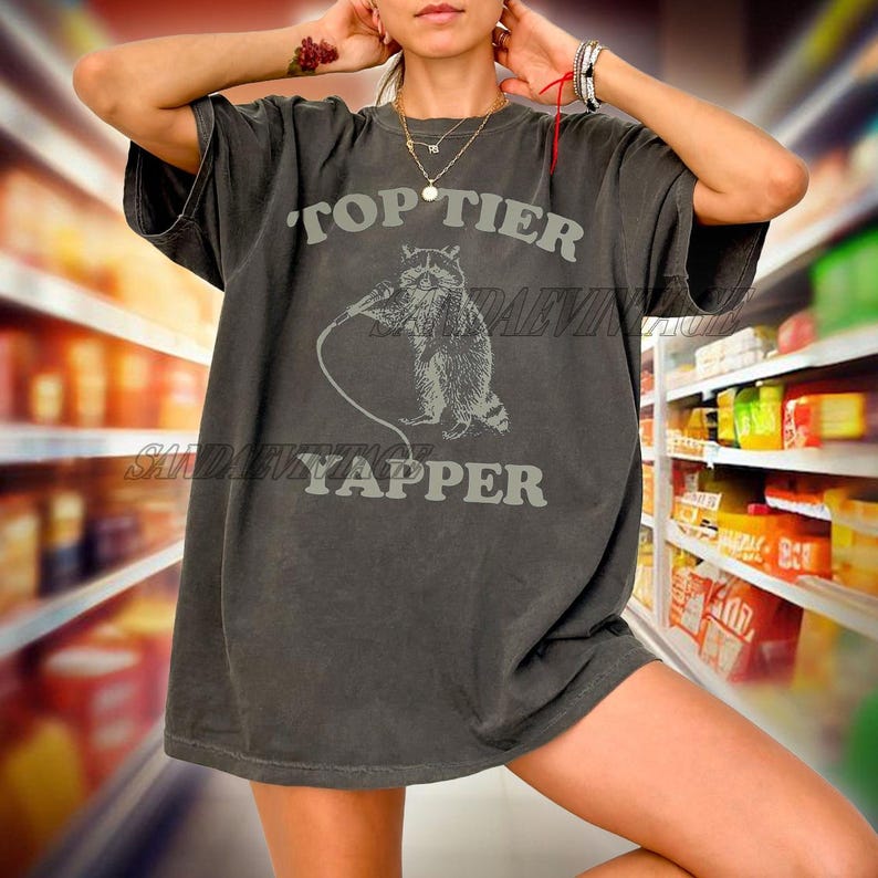 May include: A dark gray oversized t-shirt with a graphic of a raccoon holding a microphone and the text "Top Tier Yapper".