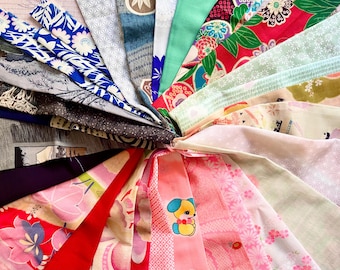 May include: A collection of colorful fabric scraps arranged in a circular pattern. The fabrics feature various patterns, including floral, geometric, and cartoon designs. The fabrics are a mix of pink, blue, green, red, and white.