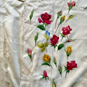 May include: Cream-colored fabric with a floral pattern featuring red, yellow, and pink roses, along with green leaves and buds. The roses are painted in a realistic style, with detailed petals and shading. The fabric has a subtle texture.
