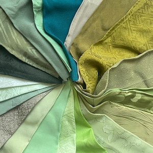 Pode incluir: Uma coleção de amostras de tecido em vários tons de verde, turquesa e branco. As amostras de tecido estão dispostas em um padrão circular, com os tons mais escuros no centro e os tons mais claros no exterior.